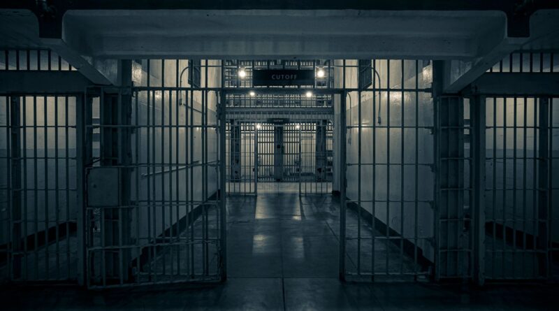 Moody interior of a prison corridor with metal bars, evoking a sense of confinement.